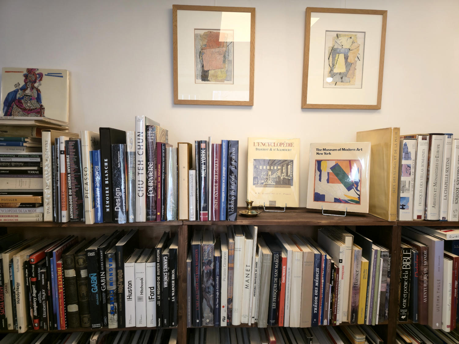 A wooden bookcase filled with books in various bindings, with two frames of