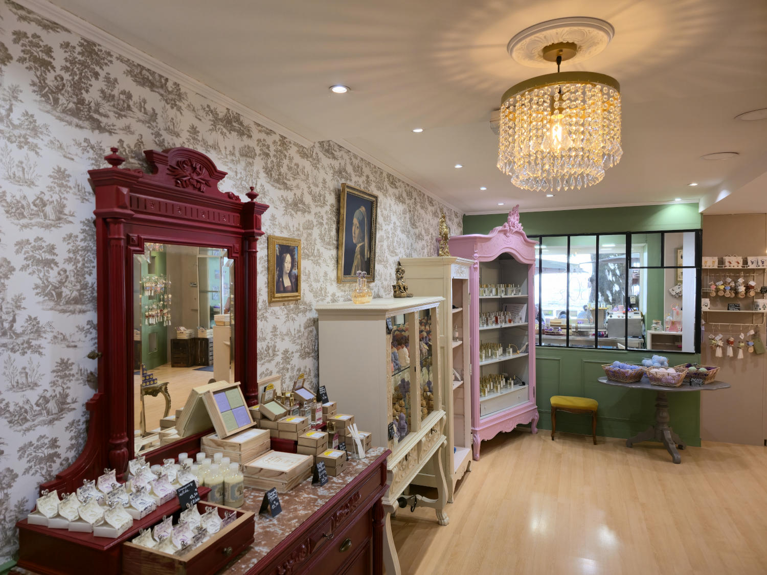 Interior of a shop decorated in a classic style, with a large red mirror, elegant furniture and products on display.