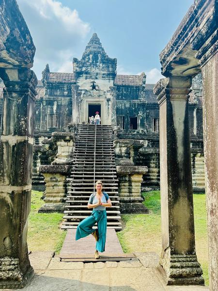 A woman does the tree pose in front of the Angkor Wat temple.
