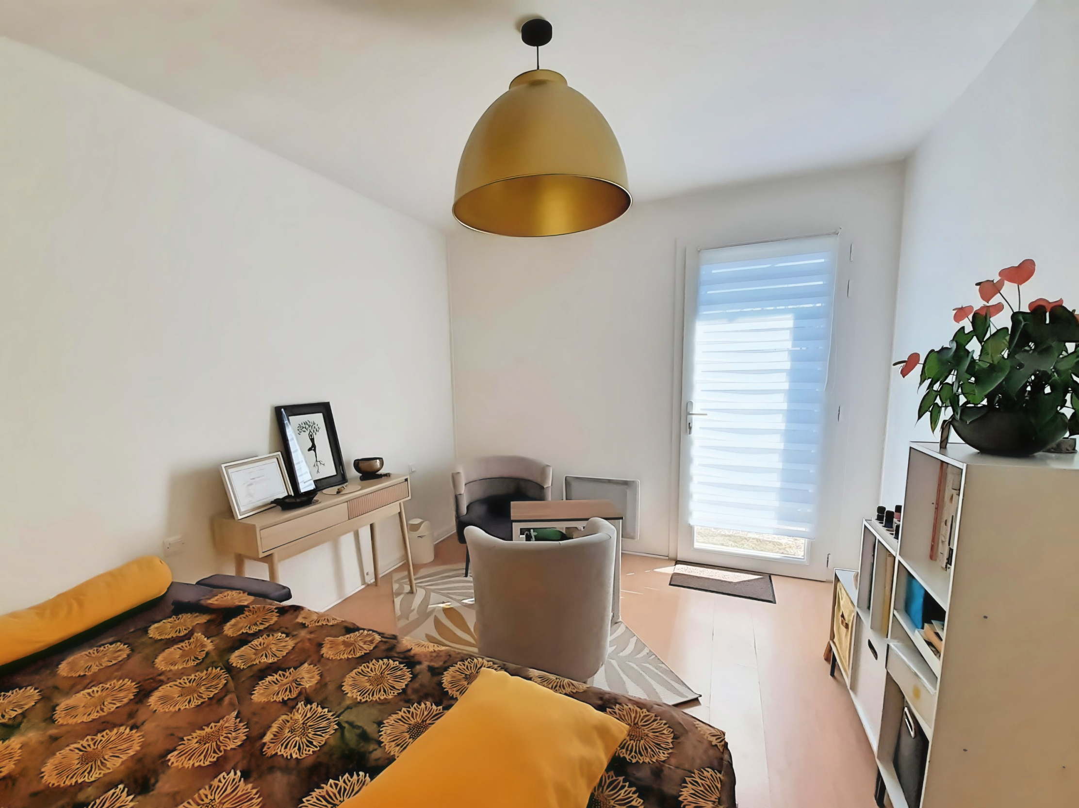 Bright, modern room with a yellow patterned sofa, desk, desk, chairs, and patio door to the outside. 