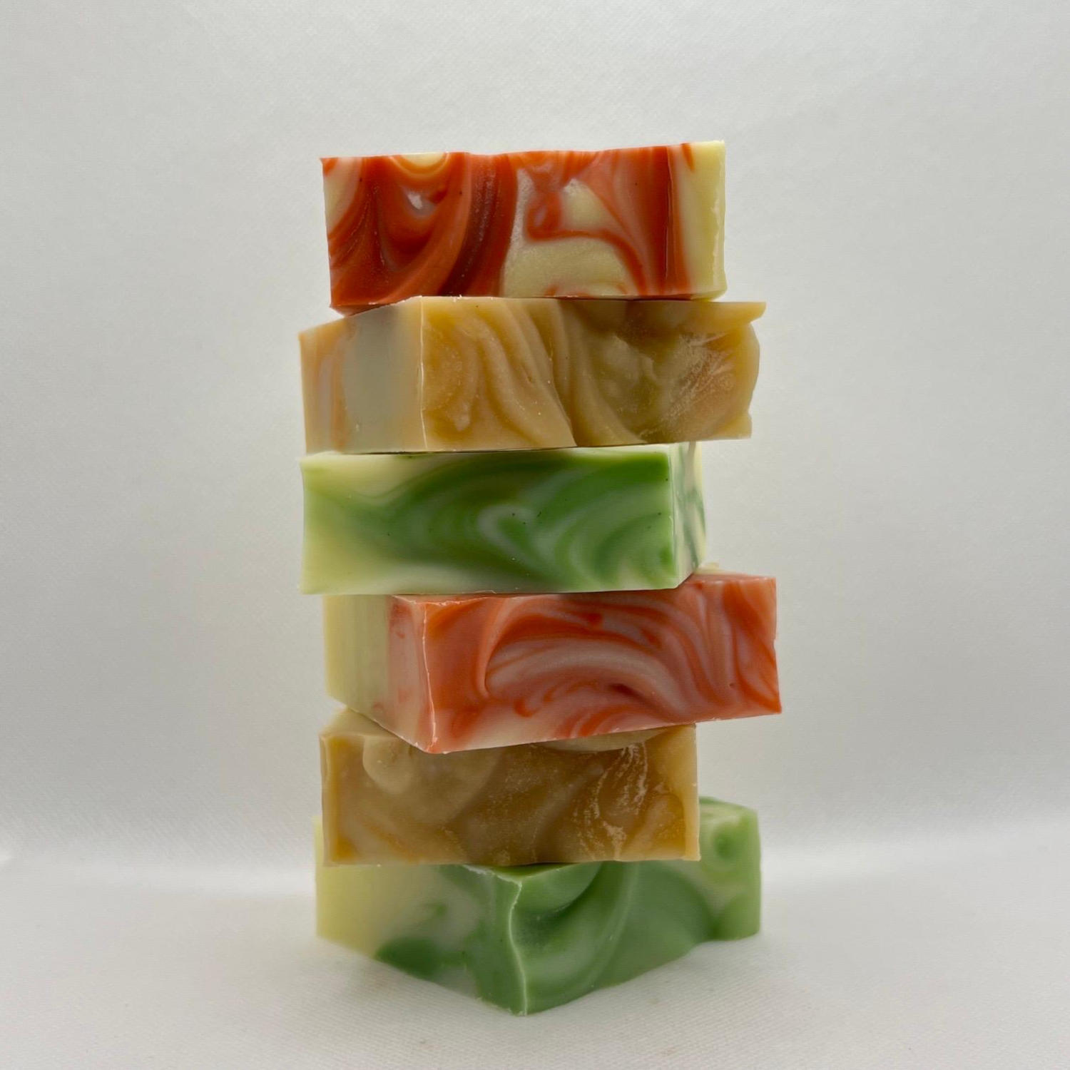A stack of six handmade soap bars with marbling patterns in various colors, such as red, green, and yellow.