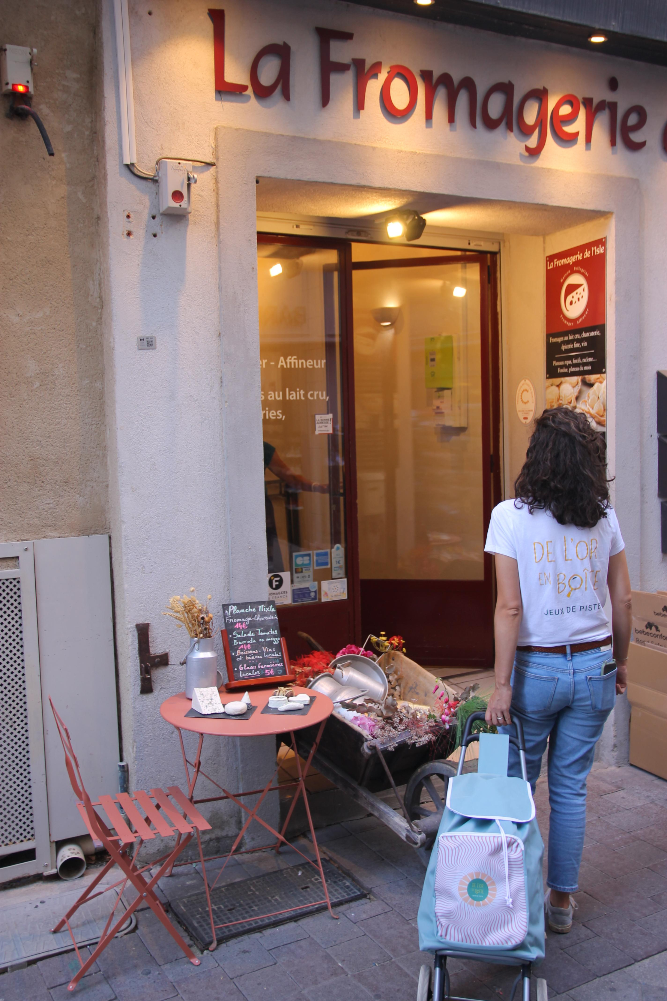 A woman seen from behind, carrying a shopping cart, walking in the direction of