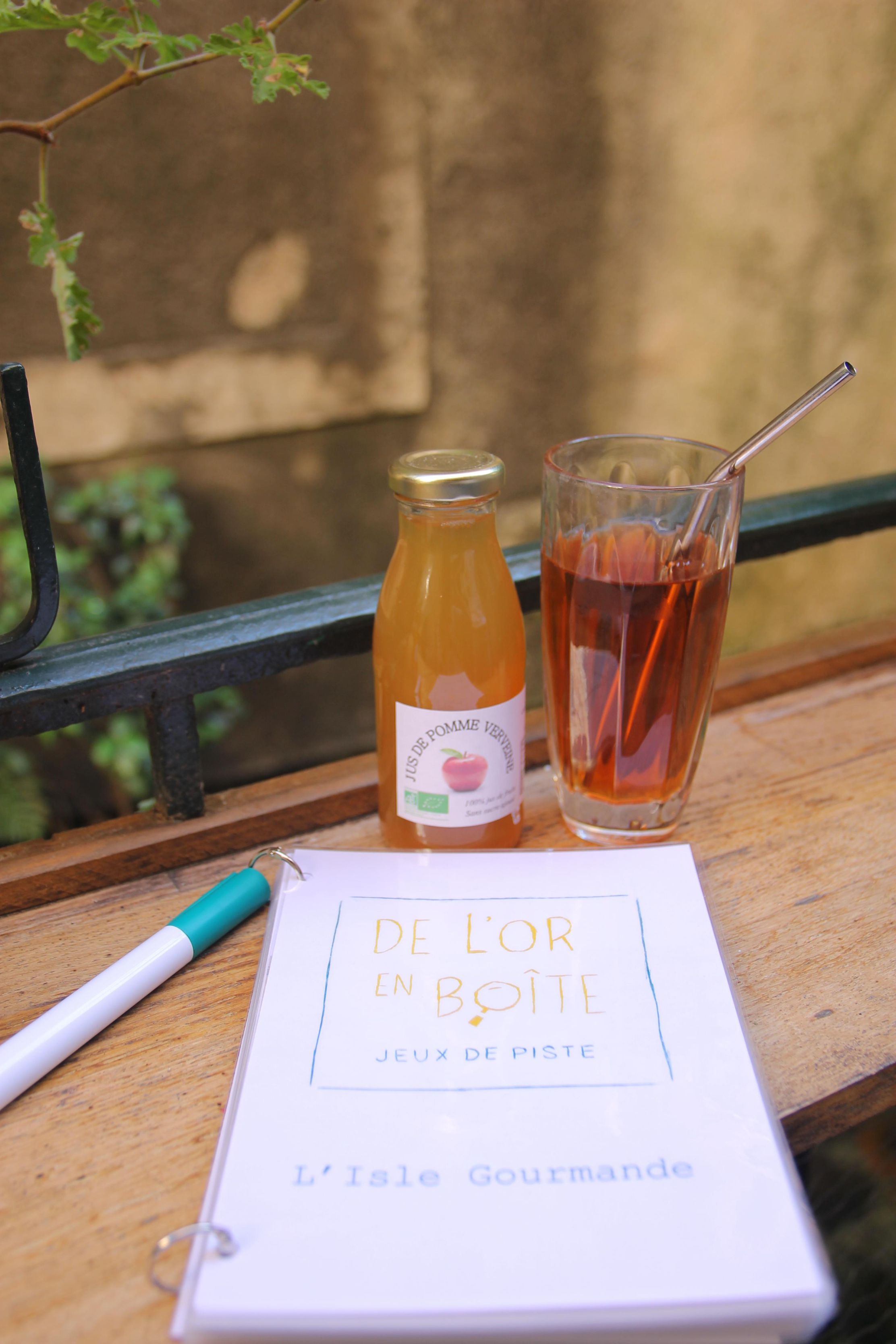 A bottle of apple juice and a glass of iced tea on a wooden table, next to