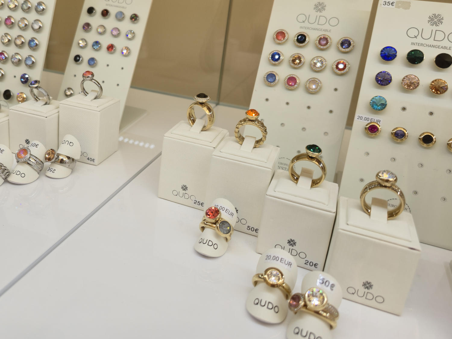 A selection of interchangeable rings and gemstones from the Qudo brand, presented in a store window.