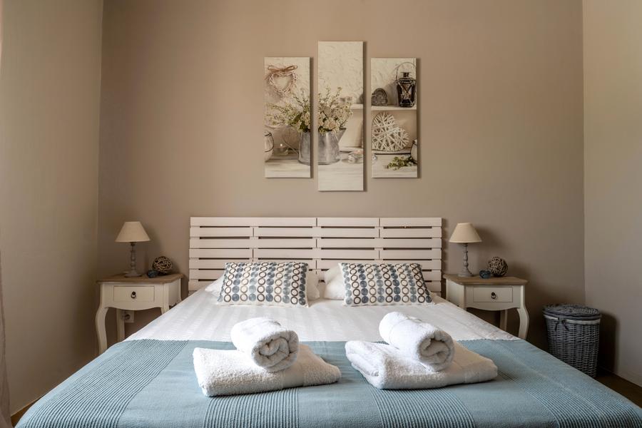Beige bedroom, sky blue bedspread, triptych on the wall and 2 white wooden bedside tables