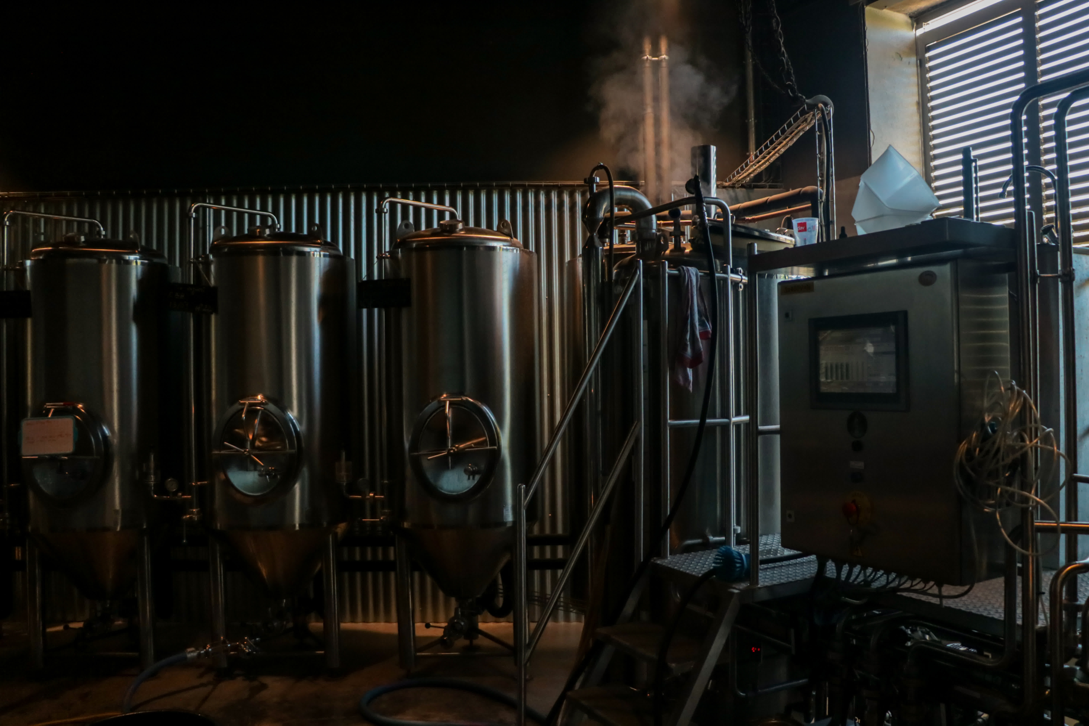 Stainless steel tanks and steam engine in a craft brewery.