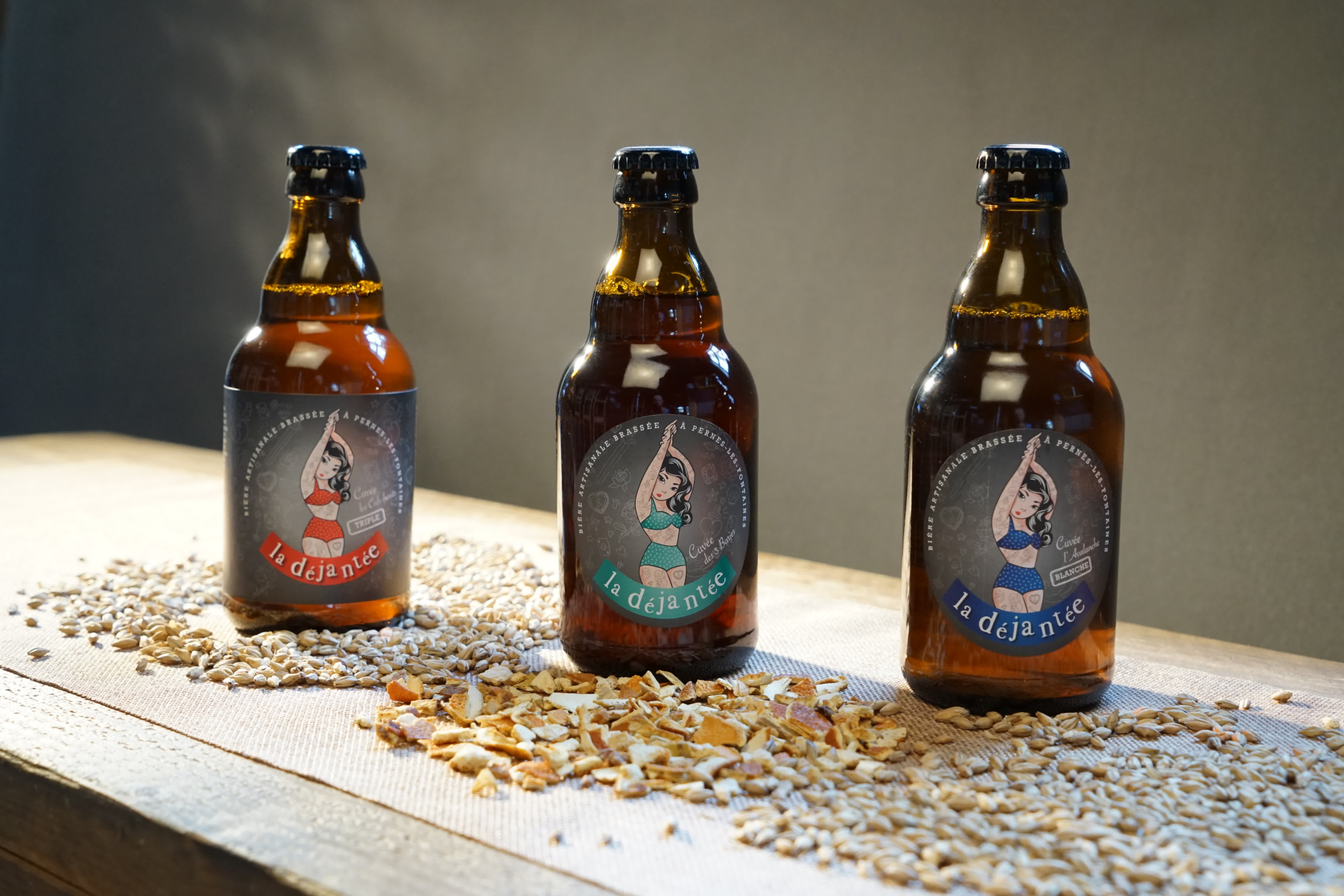 Three bottles of beer placed on a table with cereal.