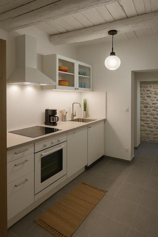 Modern and functional kitchen with clean lines, fully equipped for a stay in complete autonomy. The whitewashed exposed beams bring a warm Provençal touch to this bright and carefully renovated space.