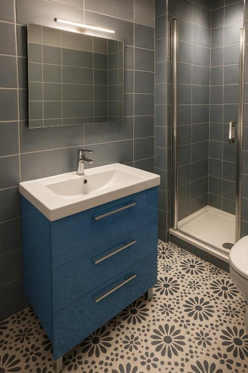 Contemporary bathroom with shower, blue vanity unit and graphic tiling on the floor. A renovated space combining modern comfort and careful decorative details.