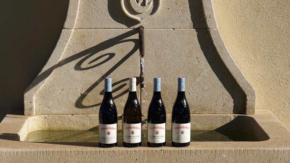 Selection of Clos du Calvaire bottles presented in front of a Provençal stone fountain. This staging illustrates the different cuvees made by the estate in the heart of