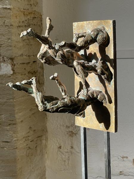 This second image shows a bronze sculpture composed of two human figures that seem to emerge from