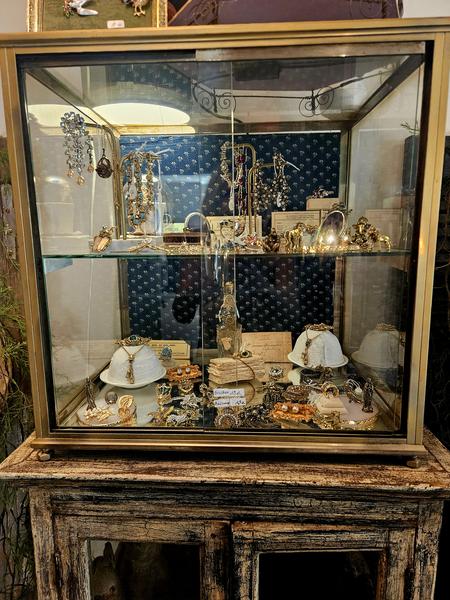 An ancient window brings together numerous costume jewelry: necklaces, bracelets, brooches, earrings and other creations. The patinated furniture and the careful presentation reinforce the vintage character of the store.