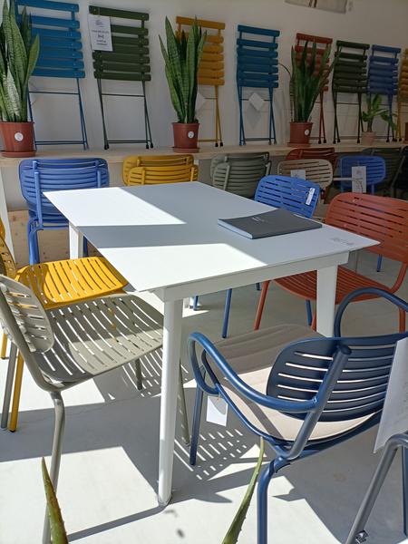 An exhibition space presents garden tables and chairs in various shades, from blue to yellow to green and red. Plants complete this staging dedicated to the layout of the terrace and the outdoors.