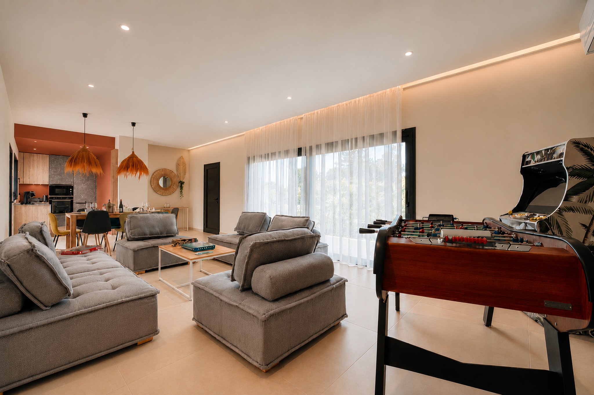 Large bright living room with open kitchen, dining area and friendly lounge. The room also has a table football and an arcade machine, ideal for sharing moments with family or friends.