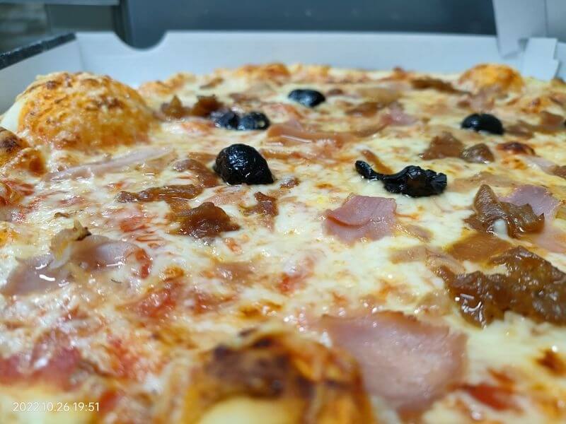 Close-up on a pizza filled with cheese, ham, olives (cheese, ham, olives), with a golden and appetizing pastry.